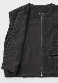 Veste en laine gris foncé avec doublure intérieure noire, fermeture éclair avant partiellement ouverte, poche rabat sur le côté droit et étiquette "OPUS" à l'intérieur du col.