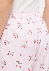 Pantaloni da pigiama a quadretti rosa con piccoli fragole rosse e fiori bianchi, dotati di un elastico in vita per il massimo comfort.