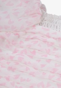 Λευκό ύφασμα με σχέδιο ροζ καρδιάς, με στρωματοποιημένες βολάν και ελαστική ζώνη μέσης με σμάλτο για ελαστικότητα και άνεση.