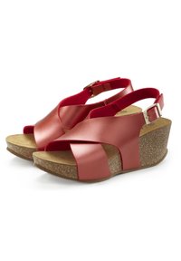 Red leather wedge sandals with cross straps and adjustable ankle buckle. Cork-style sole with textured finish. Flat footbed for comfort.