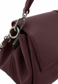 Borsa in pelle bordeaux con superficie testurizzata, forma strutturata e un dettaglio in metallo argento con tracolla regolabile.