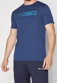 Marinblå kortärmad t-shirt i bomull med ett prickigt blått horisontellt mönster över bröstet. Slät textur och normal passform.