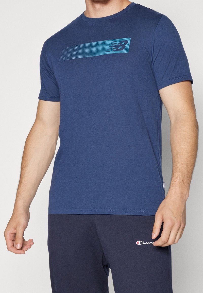 Marinblå kortärmad t-shirt i bomull med ett prickigt blått horisontellt mönster över bröstet. Slät textur och normal passform.