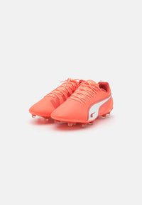Bright coral soccer cleats with a smooth synthetic upper, white side accent, six studs on each sole, and a lace-up closure.