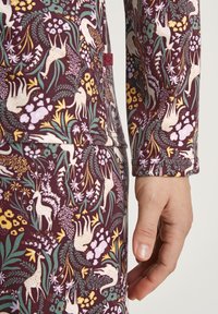 Langarm kledingstuk van bordeauxrode stof met een veelkleurig bloemen- en dierenpatroon. Inclusief een gestikte zoom en labeldetails.