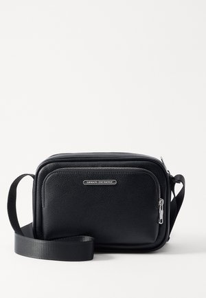 Schwarze Leder-Umhängetasche mit strukturiertem Finish, mit einem silbernen Reißverschluss und einem Logo-Schild auf der Vorderseite. Verstellbarer Stoffgurt.