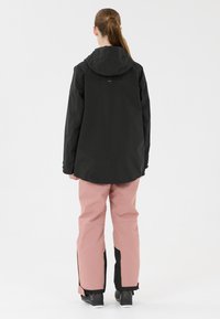 Schwarze, kapuzenbehangene, wasserdichte Jacke kombiniert mit hellrosa Schneehosen mit schwarzen Akzenten. Glatte Texture und lässige Passform mit praktischem Design.