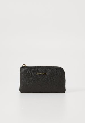Black leather wallet with a textured surface, slim rectangular shape, gold-tone hardware, and a zip closure. Gold logo prominently displayed.