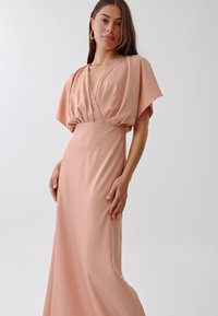 Blush pink gown with a deep V-neck, short batwing sleeves, and fitted waist, made of smooth fabric, flowing to a floor-length hem.