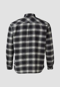 Camicia in flanella a quadri bianco e nero con colletto a bottoni, maniche lunghe e taglio dritto. Motivo a quadri ben evidente su tutto il tessuto.