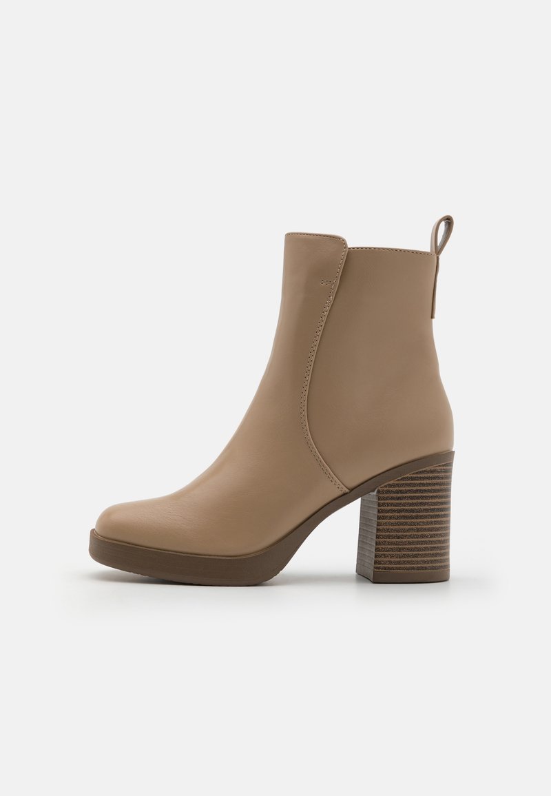 Bottine en cuir beige avec bout arrondi, talon bloc superposé et languette à l'arrière pour un enfilage facile.