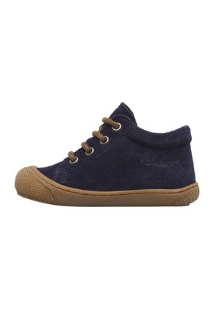 Scarpa da bambino in pelle scamosciata blu navy con suola e puntale in gomma marrone, con quattro occhielli e lacci marroni su sfondo bianco.