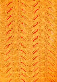 Kirjoneulosta kirkkaan oranssina siksak-kuviolla. Pintakuvio sisältää avopenkkiosiota ja hienon, yksityiskohtaisen neulostyön.