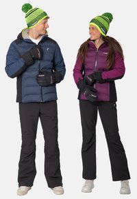 Twee personen in winterkleding. De een draagt een blauwe gewatteerde jas en zwarte broek, de ander een paarse jas en zwarte broek. Beiden dragen bijpassende gebreide mutsen.