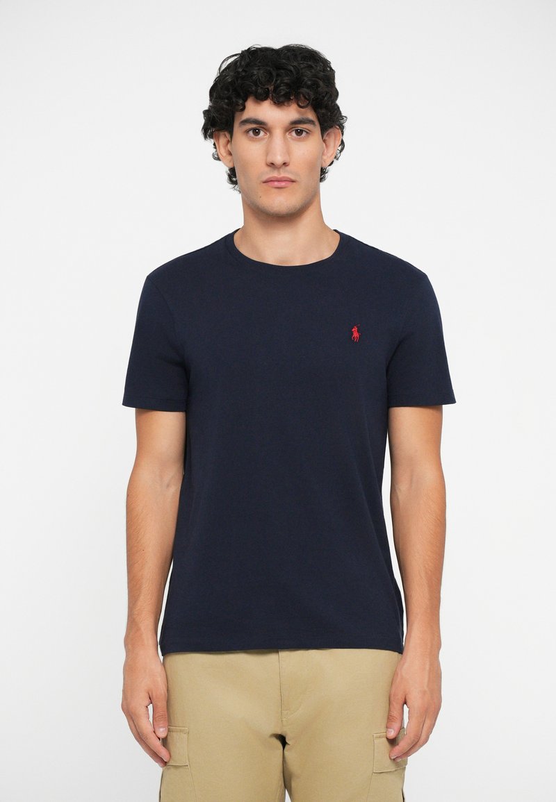Mornarsko modra majica s kratkimi rokavi, okroglim ovratom, izdelana iz bombaža, z majhnim rdečim logotipom na levem prsnem delu. Standardna prileganje.