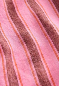 Stribet stof med nuancer af pink, brun og orange. Teksturen ser blød og let ud, med fremtrædende, jævnt fordelte lodrette striber.