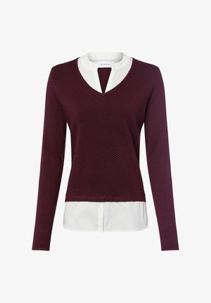 Maglione bordeaux a maniche lunghe con scollo a V indossato sopra una camicia bianca con colletto e scollatura a cuore.