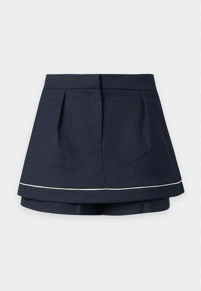 Mini-jupe superposée bleu marine foncé avec une taille haute et une fine bande horizontale blanche près de l’ourlet.