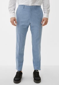 Helle blaue Hose aus strukturiertem Stoff, mit einem schlanken Design und maßgeschneiderter Passform, kombiniert mit schwarzen Sneakers.