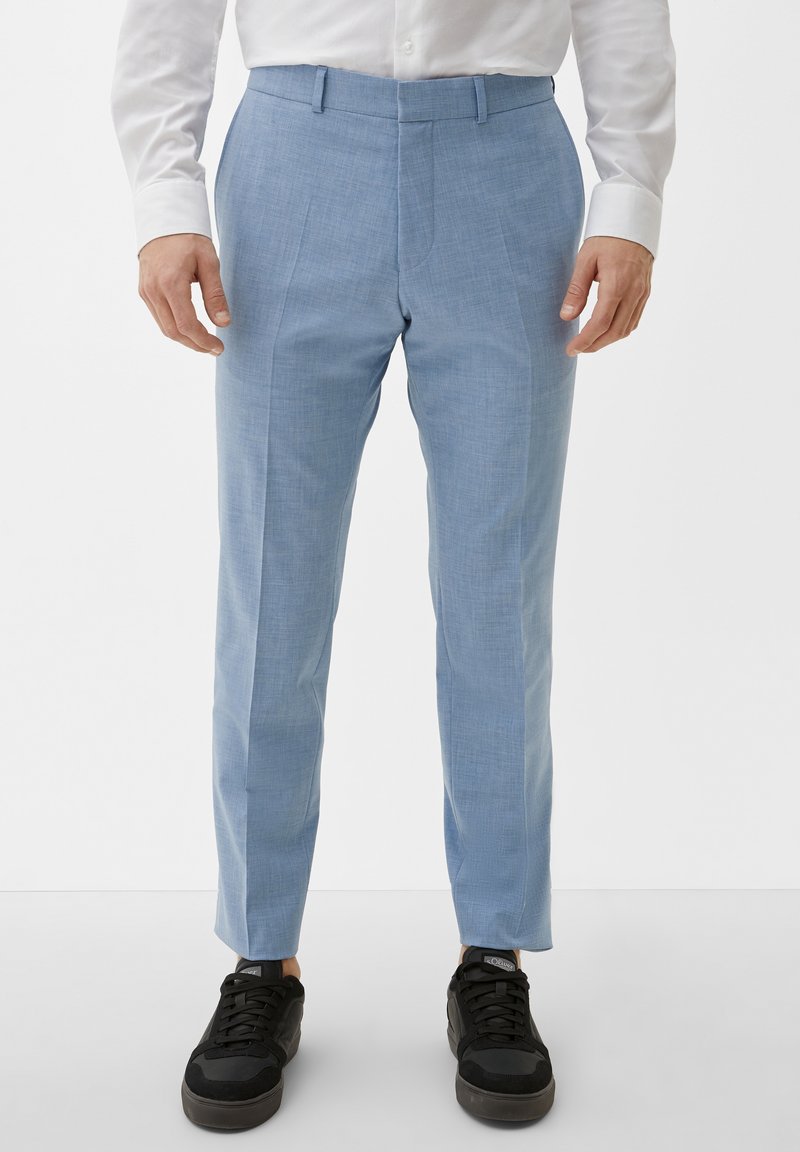 Helle blaue Hose aus strukturiertem Stoff, mit einem schlanken Design und maßgeschneiderter Passform, kombiniert mit schwarzen Sneakers.