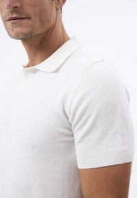 Kurzarm-Polohemd aus leichtem beigem Baumwollmix, mit geripptem Kragen und Bündchen, glatter Textur und taillierter Silhouette.