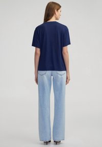 Navyblauwe katoenen T-shirt met een losse pasvorm, korte mouwen en een ronde halslijn, gecombineerd met lichtblauwe wijde jeanstype.