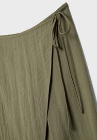 Olivgrüner Stoffwickelrock mit einem Seitenschlitz und verstellbarem Bindeband in der Taille, aus leichtem, strukturiertem Material gefertigt.