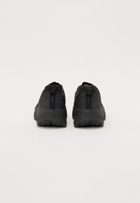 Des chaussures de course noires avec un dessus en tissu texturé, un talon renforcé et une semelle en caoutchouc épaisse dotée d'un motif de semelle prononcé.