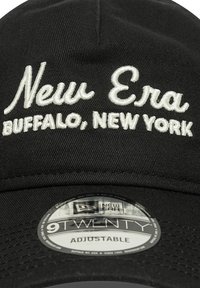 Črna kapa New Era z belim vezenim napisom "New Era" in "Buffalo, New York." Ima nastavljiv trak in okroglo oznako z napisom "9TWENTY."