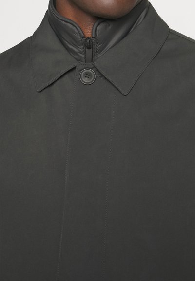 Abrigo negro de corte trench con un alto collar, cierre de botón único y textura suave, con costuras tonales para una apariencia elegante.