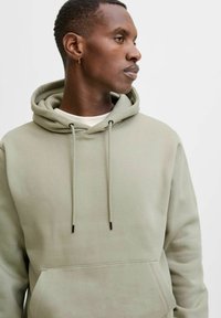 Felpa con cappuccio verde chiaro, dotata di tasca a marsupio, cordini e una sottile trama. Design semplice e casual con un taglio moderno.