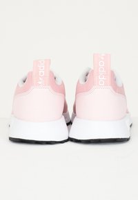 Pink athletic shoes with a smooth synthetic upper, white soles, and prominent branding on the heel. Features a streamlined design and rounded shape.