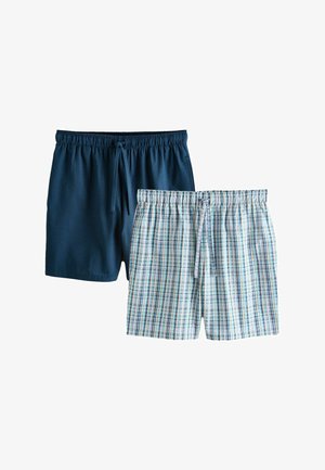 Dva páry pánských kraťasů s elastickým pasem, jedny jednobarevné tmavě modré a druhé bílé s modro-zeleným károvaným vzorem, obě se šňůrkami na stažení.