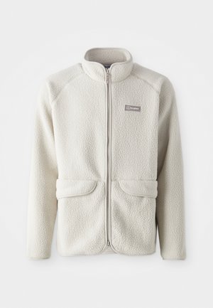 Fleece takki vaalean valkoisena, täysipitkällä vetoketjulla, raglan-hihoilla, kahdella etutaskulla ja pienellä logolla vasemmassa rintataskussa.