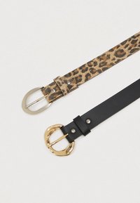 Dva pasova: en leopard vzor izsušena z mehkimi zaponkami in en črn usnjen z zlatimi zaponkami ter kovinskimi detajli.