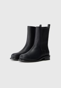 Black leather ankle boots with a smooth texture, elastic side panels, round toe, and a low block heel for stability.