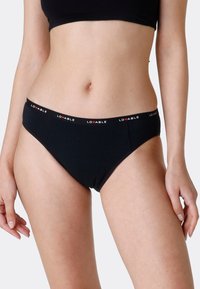 L'intimo bikini nero presenta un tessuto liscio, una forma a vita media e un elastico con il marchio, caratterizzato da scritte rosse e bianche.