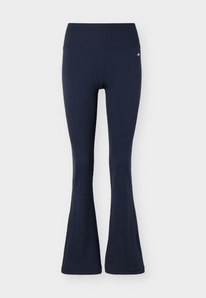 Μπλε ναυτικό ψηλόμεσο κολάν με φαρδιά καμπάνα και μικρό άσπρο λογότυπο στο πάνω μέρος του αριστερού μηρού, σε απλό φόντο.