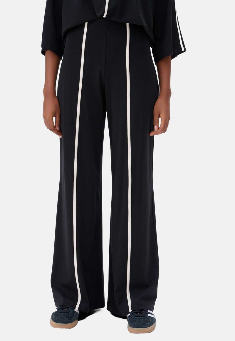 Zwarte wijde broek met verticale witte strepen, zachte stof, hoge taille, met een elastische tailleband en contrasterende accenten.