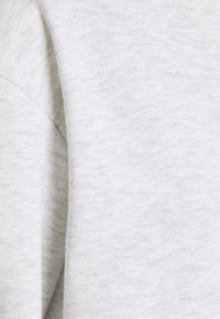 Tessuto grigio chiaro con una texture liscia, caratterizzato da un delicato motivo melangiato e una vestibilità comoda. Vista ravvicinata della superficie del materiale.