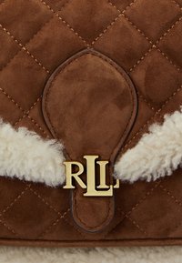 Borsa a tracolla in suede marrone con design trapuntato, caratterizzata da un accento in shearling crema e una chiusura con logo dorato "RLL". Aspetto morbido e texture raffinata.