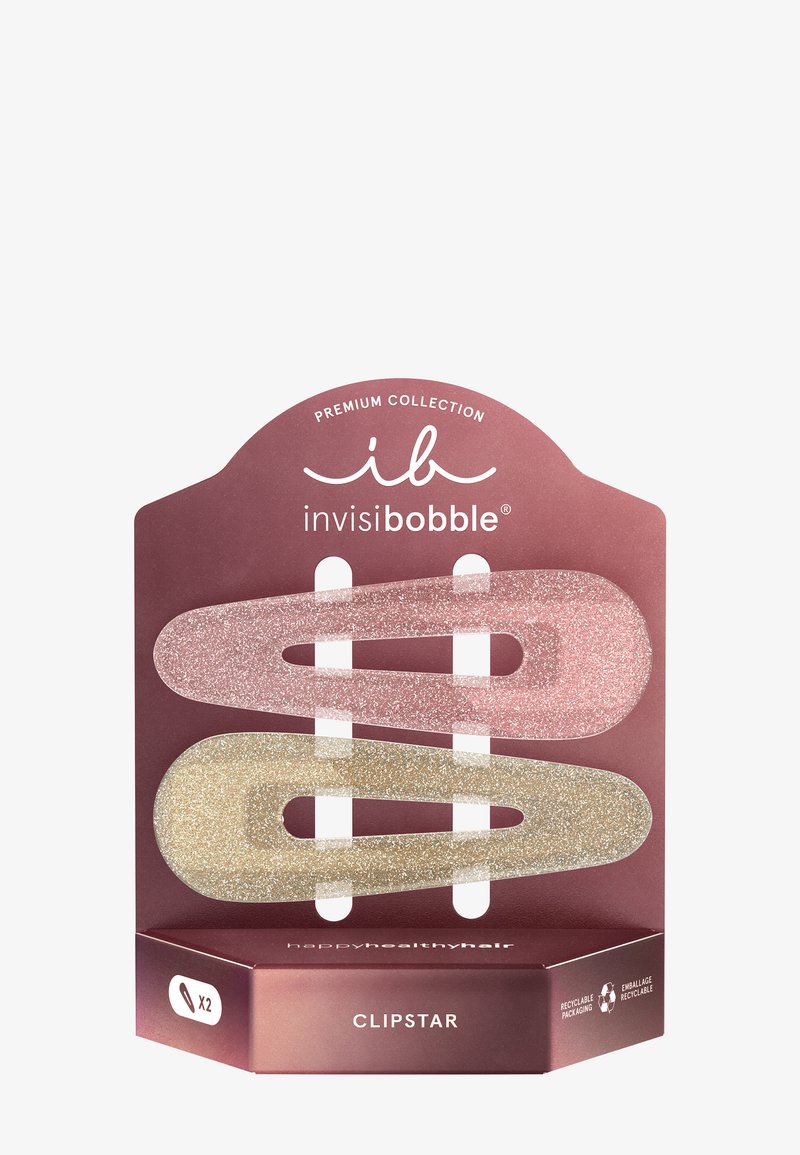 Deux barrettes pailletées, une rose et une dorée, présentées sur un emballage mauve étiqueté « invisibobble CLIPSTAR » avec des symboles recyclables.