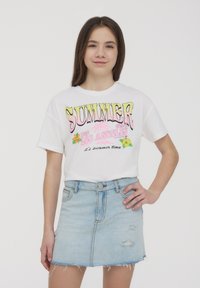 Maglietta bianca in cotone con grafica colorata "SUMMER 1962 LOS ANGELES"; abbinata a una gonna in denim azzurro chiaro con orlo sfilacciato e leggere scoloriture.