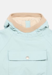 Ανοιχτό μπλε μπουφάν με μπεζ ριμπ γιακά, με τσέπη μπροστά και λεπτομέρεια με κουμπί. Το υλικό φαίνεται λείο και ανθεκτικό στο νερό.