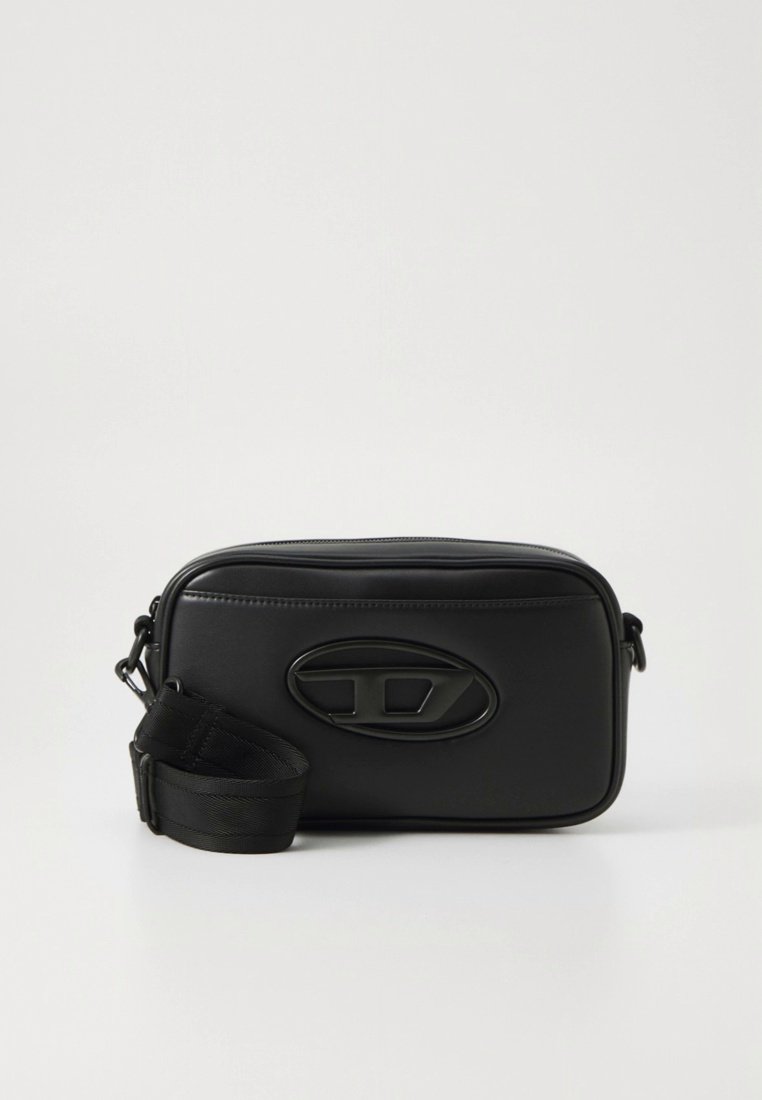 Sac bandoulière en cuir noir à texture lisse, forme rectangulaire, logo ovale sur le devant et bandoulière réglable. Fermeture éclair en haut.