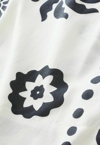 Zwart bloemenpatroon op witte stof, met grote en kleine bloemen met onderscheidende vormen en contouren, een zachte textuur en een lichte glans.
