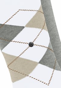 Weiße Socken mit einem Argyle-Muster in Grau, Beige und Braun, sichtbaren Nähten und einem schwarzen runden Logo an der Seite.