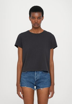 Črna skrajšana majica s kratkimi rokavi, okroglo dekolte in mehko teksturo. V kombinaciji z uničenimi denim kratkimi hlačami. Preprost dizajn in prileganje.
