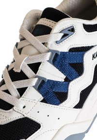 Sneaker con tomaia in pelle bianca e rete blu navy, con un design testurizzato. Lacci blu e bianchi intrecciati attraverso hardware grigio.