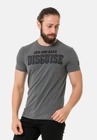 Graues T-Shirt mit kurzen Ärmeln aus weichem Stoff, das auf der Vorderseite einen auffälligen Grafikdruck "CIPO AND BAXX DISGUISE" in dunklen Farben zeigt.